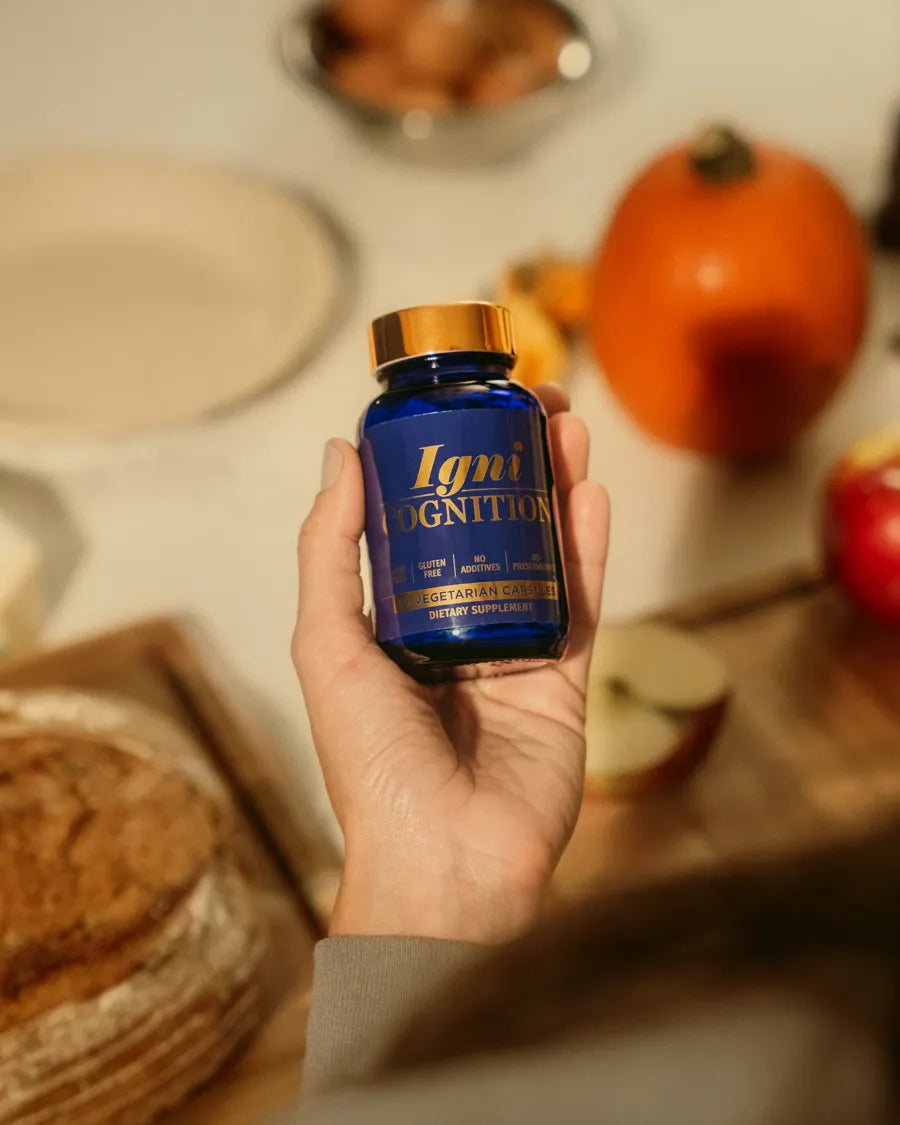 A hand holding a bottle of IgniCognition in a sunlit autumn kitchen