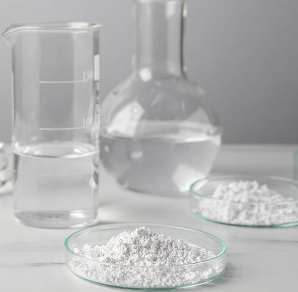 NADH – Laboratory setup with beakers, flasks, and a dish of white powder on a light gray background