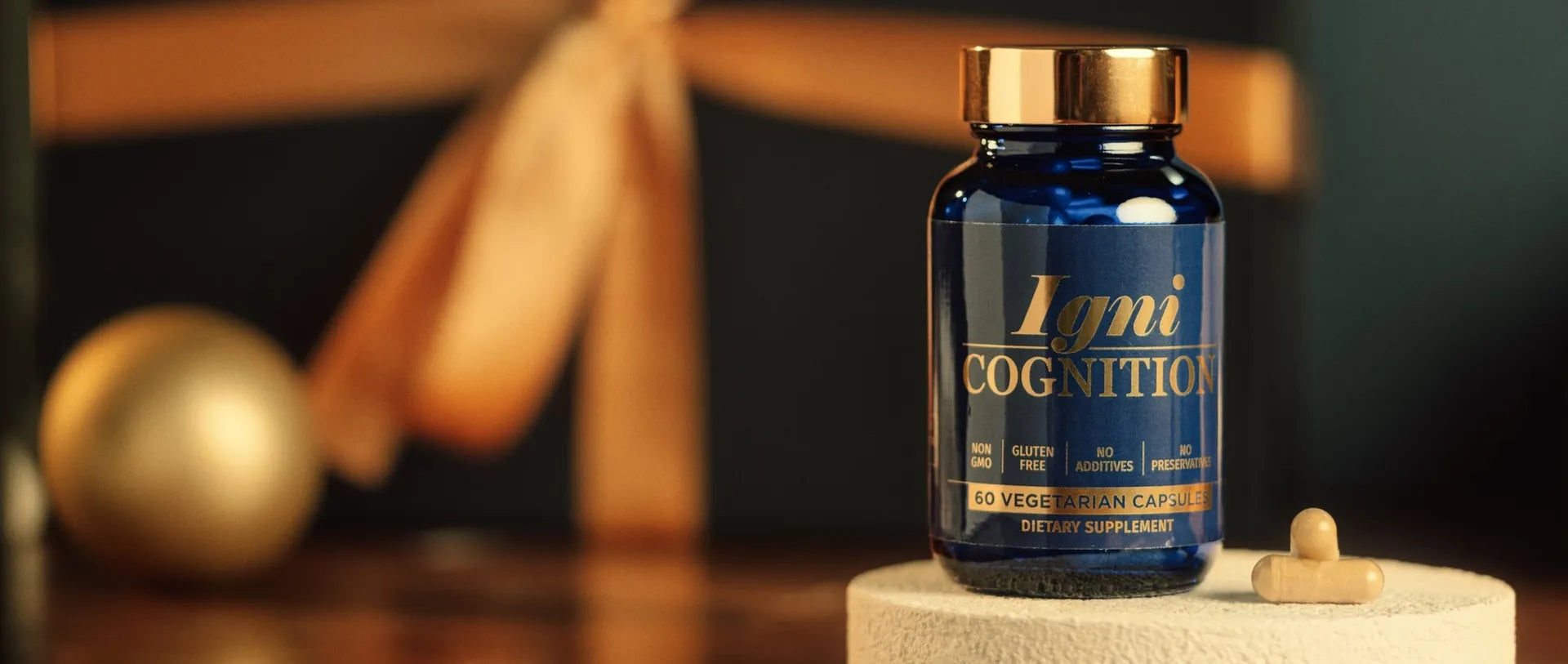 A bottle of IgniCognition on a stone plinth in front of a gift with a gold bow