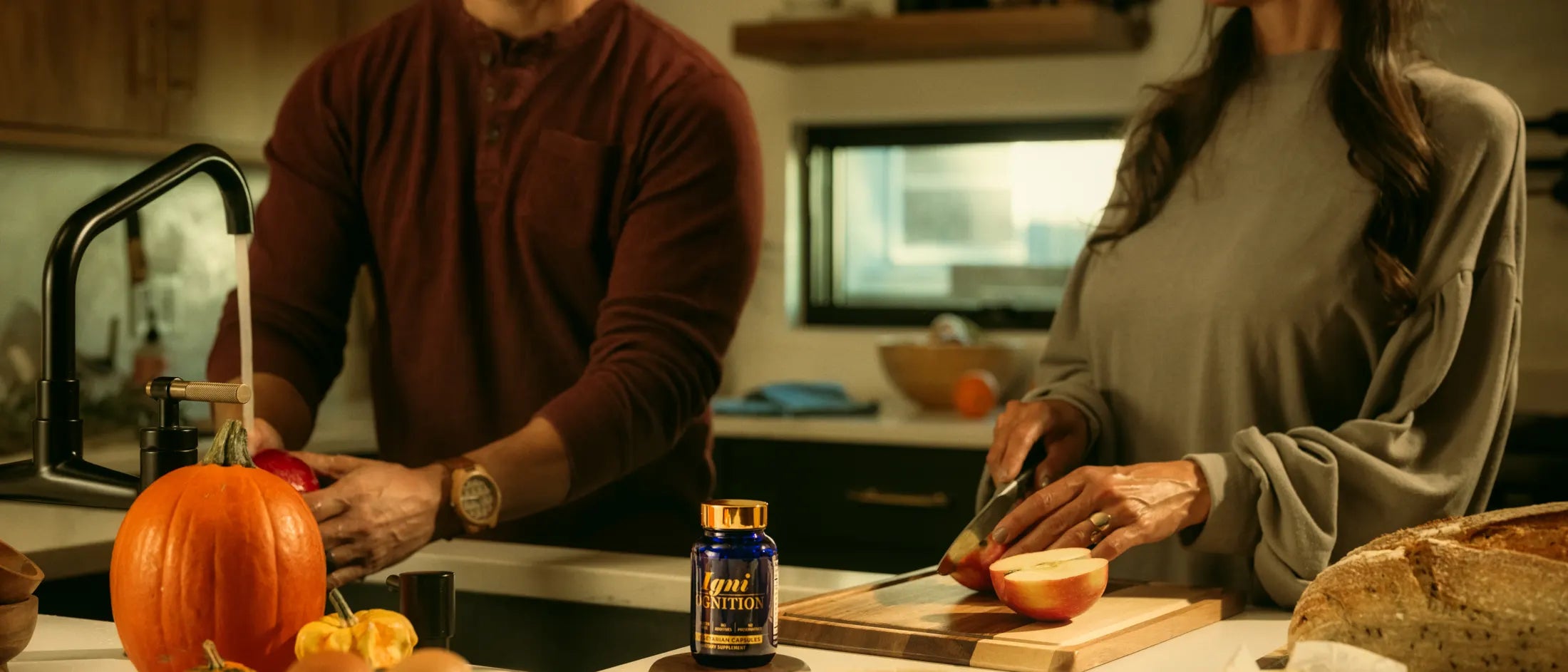A couple cooking together in a sunlit autumn kitchen with IgniCognition on the counter